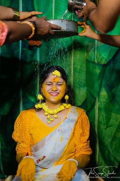 a woman is getting her face painted with yellow and white paint while others are washing her hands