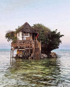 a house on an island in the middle of the ocean with stairs leading up to it