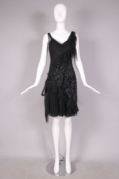 Vintage John Galliano bias cut black silk and silver lurex threaded cut velvet cocktail dress with cowl neckline, diagonal ruffles and long silk ties at a single shoulder and its opposite hip. Comes with a silk slip underneath. In excellent condition. Labeled a Size 6 but more likely will fit a size 4. MEASUREMENTS: Bust - 30" Waist - 25-26" Hip - 36" Length - 40" Elegant Evening Flapper Dress, Elegant Fitted Flapper Dress For Evening, Elegant Black Flapper Dress For Formal Occasions, Elegant Black Flapper Dress For Evening, Sleeveless Silk Flapper Evening Dress, Elegant Silk Flapper Dress For Formal Occasions, Elegant Silk Flapper Dress For Evening, John Galliano Dress, Galliano Dress