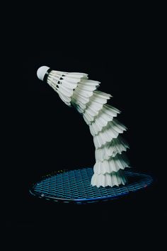 a white bird is flying over a blue object on a black surface with light coming from it's wings