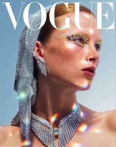 a woman with glitter on her face and neck, wearing large silver jewelry in front of the cover of a magazine