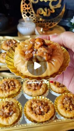 someone is holding up some food in front of other small pastries on a tray