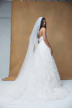 a woman in a white wedding dress is posing for the camera while wearing a veil