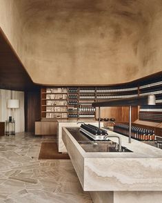 a large kitchen with marble counter tops and wooden shelves filled with wine bottles on the wall