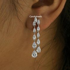 a woman's ear is shown with three tear shaped earrings on top of it