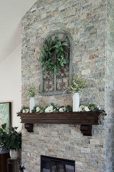 a living room with a stone fireplace and potted plants on top of the mantle