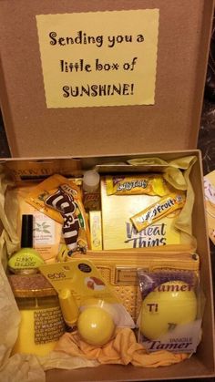 a box filled with lots of different items next to a sign that says sending you a little box of sunshine