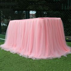 a pink table cloth on top of a lush green field