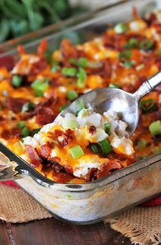 a casserole dish with meat, cheese and green onions on top is being spooned