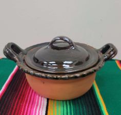 a brown pot sitting on top of a colorful table cloth