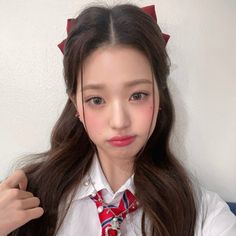 a girl with long brown hair wearing a white shirt and red bow tie