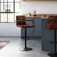 two brown leather barstools sit in front of a kitchen counter with an area rug on the floor