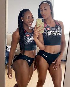 two women in matching sports bras taking a selfie with their cell phone while standing next to each other