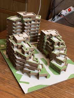 a paper model of some buildings sitting on top of a wooden table next to a computer mouse