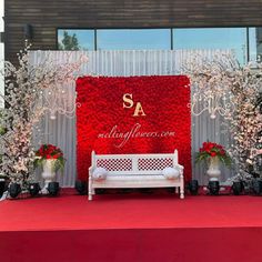 a white bench sitting in front of a red backdrop with flowers and candles on it