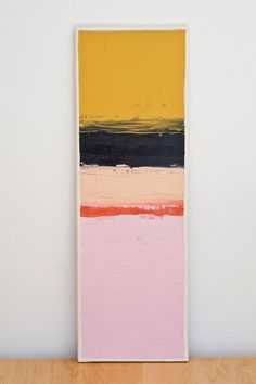 a painting is displayed on a shelf in front of a white wall and wooden table