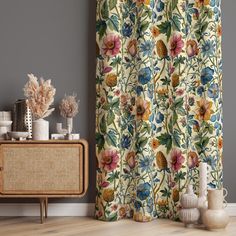 a living room with floral curtains and vases on the side table next to it