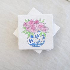 three coasters with pink flowers in a blue and white vase on a linen tablecloth