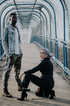 two people standing on a bridge with one holding the leg of another person's hand