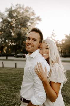 a man and woman hugging each other in the grass