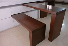 a wooden table and bench in a room with white tile flooring on the walls