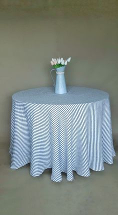 a blue and white striped tablecloth with flowers in a vase sitting on the top