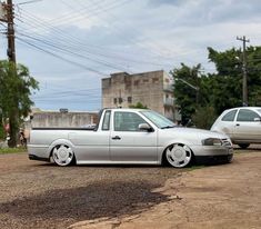 a silver car parked on the side of a dirt road next to another white car