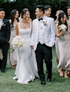 a bride and groom walking with their wedding party