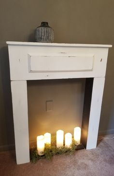 three lit candles sitting on top of a white fireplace