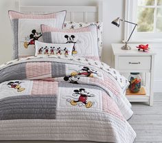 a bed with mickey mouse comforter and pillows