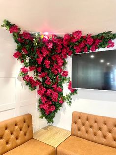 a living room with two couches and a television mounted to the wall covered in pink flowers