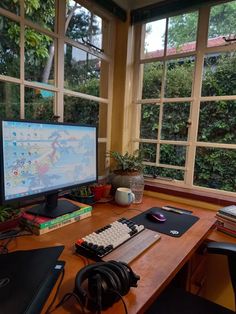 a desk with a computer monitor, keyboard and mouse on it in front of large windows