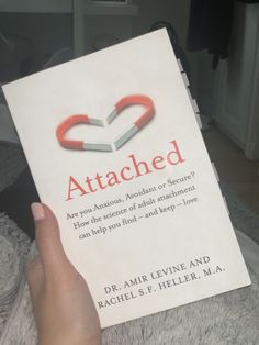 someone holding up a book about attached