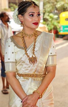 a woman in a white sari and gold jewelry