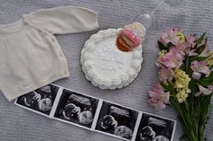 a baby's first birthday cake, flowers and photos are laid out on a blanket