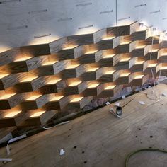 a wall made out of wooden blocks with lights on it and some tools laying around