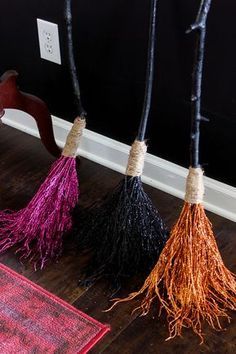 three brooms are sitting on the floor next to a rug and a light switch