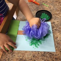 a young child is making an art project with tissue paper and construction materials on the table