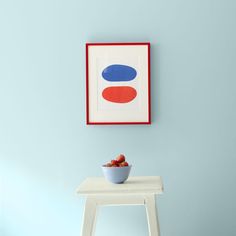 a bowl of fruit is sitting on a small table in front of a blue wall