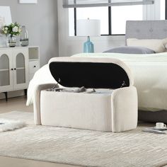 an open suitcase sitting on the floor in front of a bed with white sheets and pillows