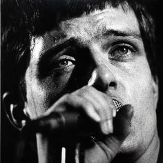 a black and white photo of a man holding a microphone to his mouth with one hand