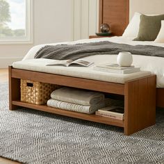 a bed with a wooden frame and white linens on the bottom shelf next to it