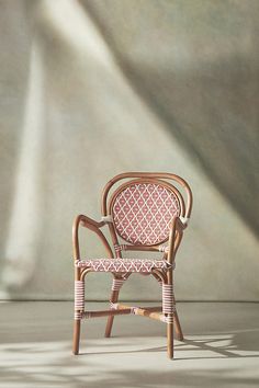 a wicker chair sitting in front of a wall with a shadow on the floor