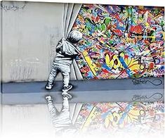 a young boy standing in front of a graffiti covered wall with his reflection on the ground