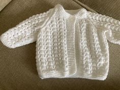 a white knitted sweater sitting on top of a couch