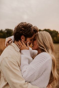 a man and woman embracing each other in an open field