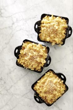 three small black dishes filled with macaroni and cheese