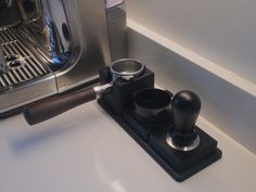 a close up of a coffee maker on a counter with a cup holder in front of it