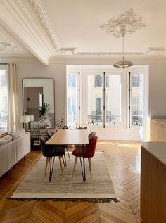 a living room filled with furniture and a dining table in front of a large window