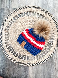 a blue, red and white knitted hat with a pom - pom